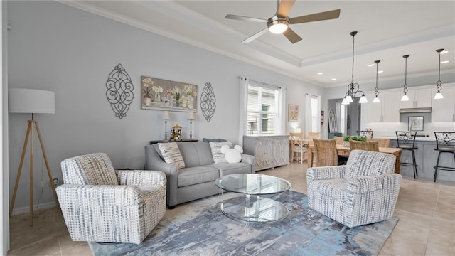 living room with light tile flooring, a tray ceiling, ornamental molding, and ceiling fan