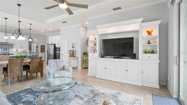 tiled living room with ceiling fan, sink, built in features, a raised ceiling, and crown molding