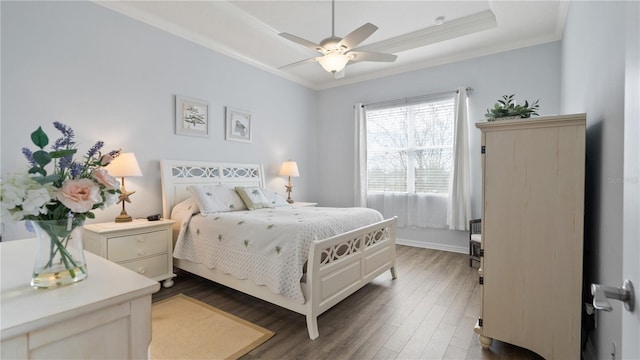 bedroom featuring a tray ceiling, ornamental molding, ceiling fan, and dark hardwood / wood-style flooring