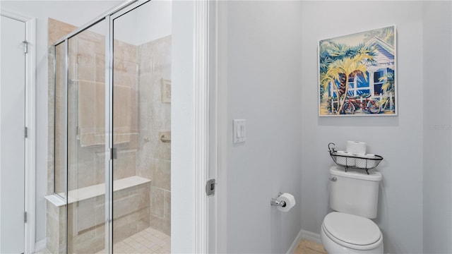 bathroom featuring toilet, tile floors, and a shower with shower door