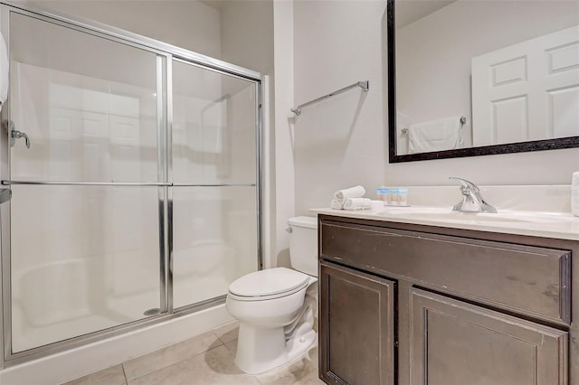 bathroom with toilet, vanity, a shower with door, and tile flooring