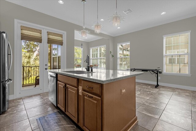 kitchen featuring an island with sink, sink, light tile floors, hanging light fixtures, and stainless steel appliances