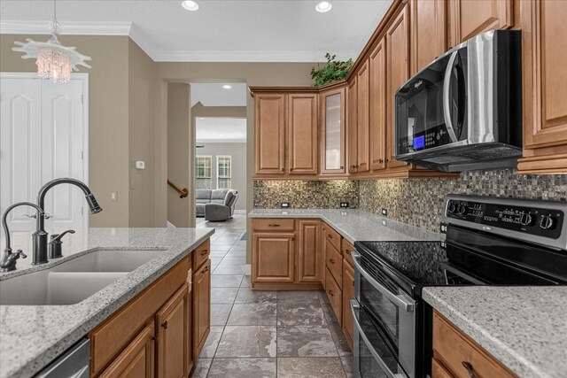 kitchen with an inviting chandelier, appliances with stainless steel finishes, tasteful backsplash, and light stone counters