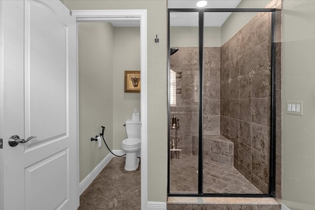 bathroom with a shower with door, tile floors, and toilet