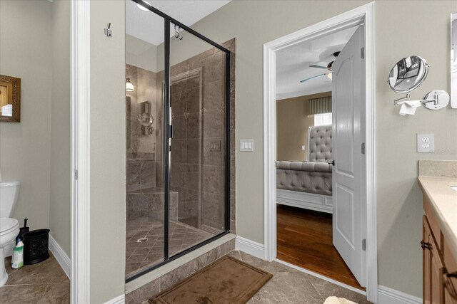 bathroom featuring toilet, ceiling fan, a shower with shower door, tile flooring, and vanity