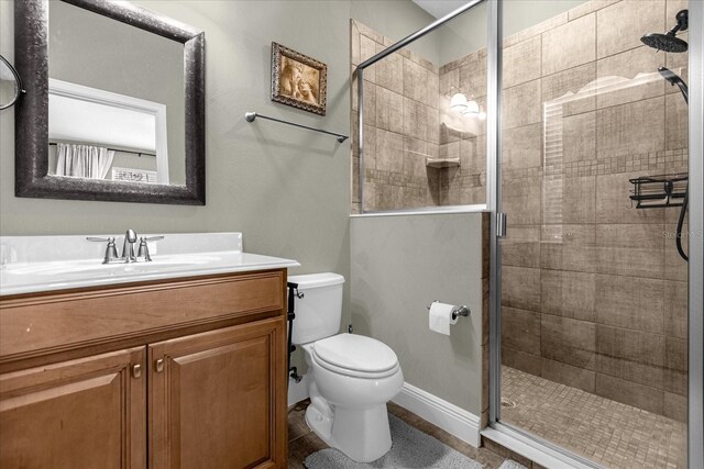 bathroom featuring toilet, a shower with door, and vanity