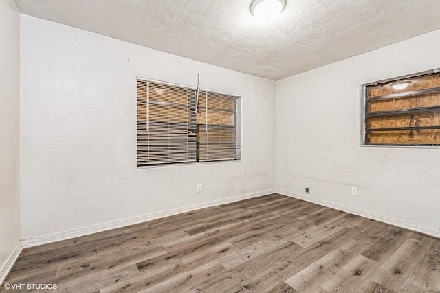 spare room with a textured ceiling and dark wood-type flooring