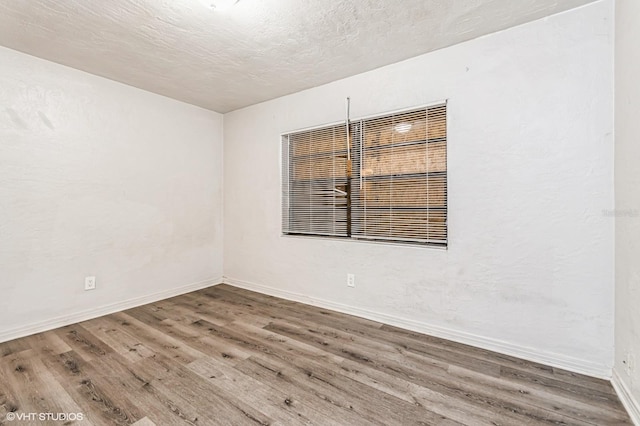 empty room featuring wood-type flooring and a textured ceiling