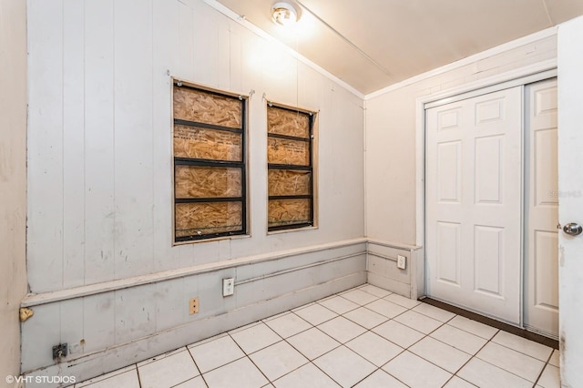 interior space with light tile patterned flooring, vaulted ceiling, and ornamental molding