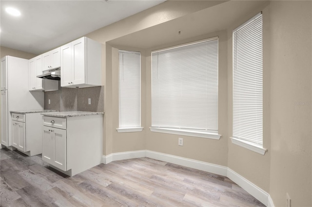 kitchen with white cabinets, plenty of natural light, light hardwood / wood-style flooring, and backsplash