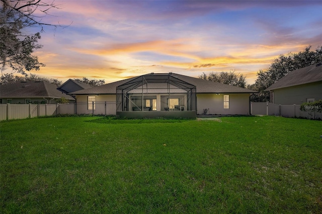 back house at dusk featuring a yard and a lanai