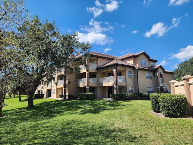 rear view of property featuring a lawn and a balcony