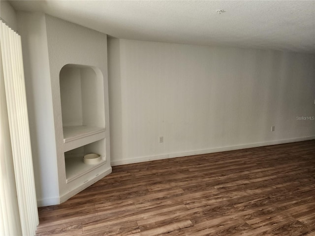 interior space featuring built in features, dark wood-type flooring, and a textured ceiling