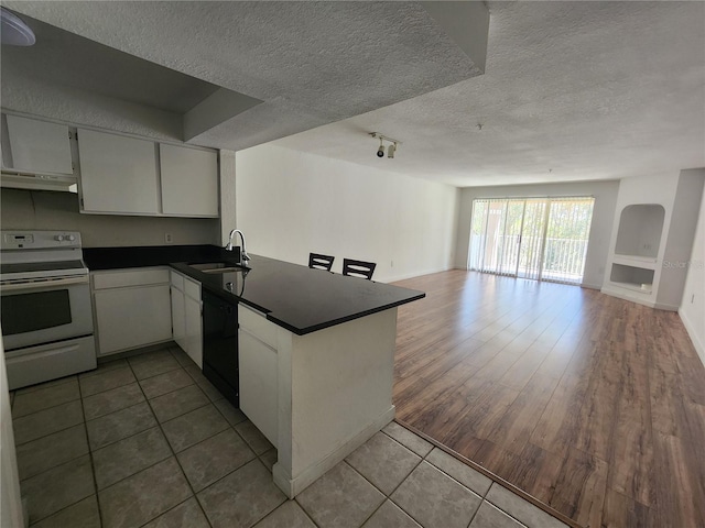 kitchen with kitchen peninsula, white range with electric cooktop, a textured ceiling, tile flooring, and dishwasher