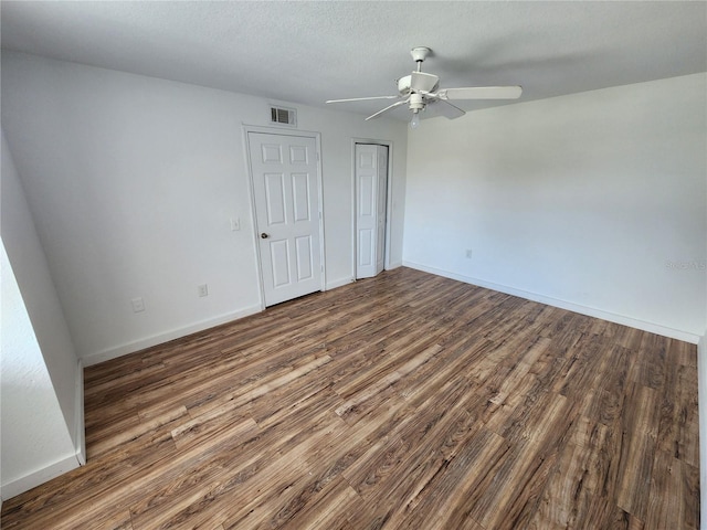 spare room with ceiling fan, a textured ceiling, and dark wood-type flooring