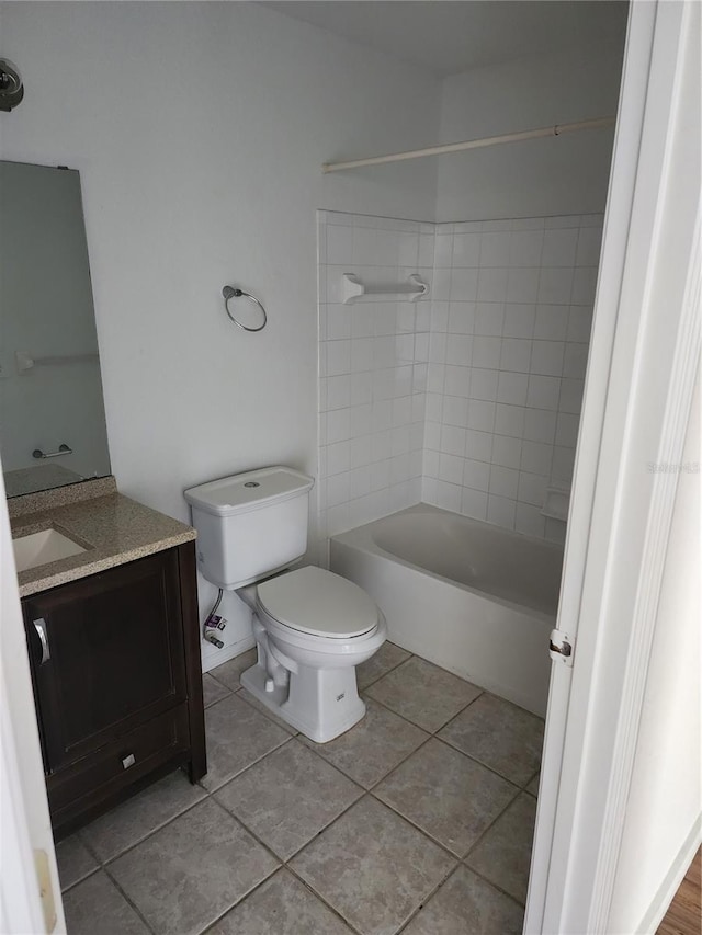 full bathroom with tiled shower / bath, toilet, tile floors, and vanity