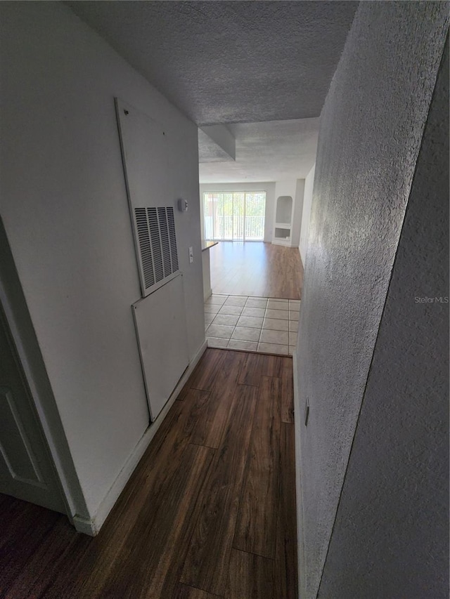 hallway featuring a textured ceiling and tile floors