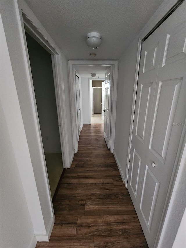 hallway featuring a textured ceiling and dark hardwood / wood-style floors