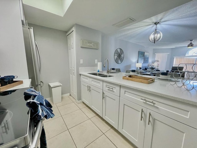 kitchen featuring white cabinetry, ceiling fan with notable chandelier, sink, light tile floors, and stainless steel refrigerator