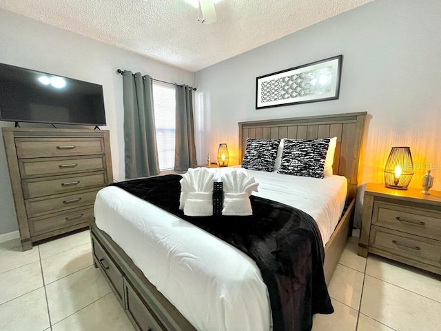 bedroom featuring ceiling fan, light tile floors, and a textured ceiling