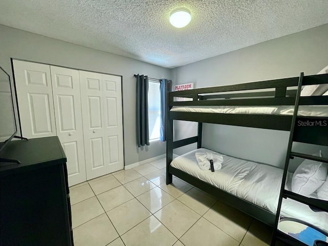 bedroom featuring a closet, light tile floors, and a textured ceiling