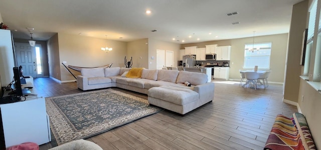 living room with light wood-type flooring and a notable chandelier