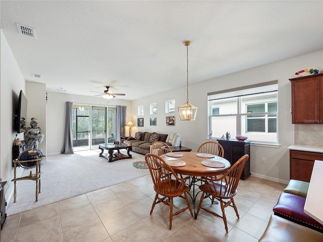 dining area with light carpet, a textured ceiling, plenty of natural light, and ceiling fan with notable chandelier