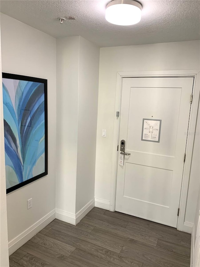 doorway to outside with a textured ceiling and dark wood-type flooring