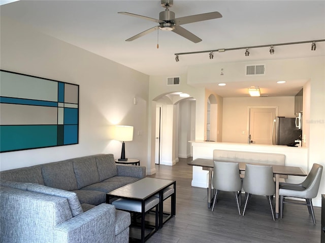 living room with dark wood-type flooring, ceiling fan, and rail lighting