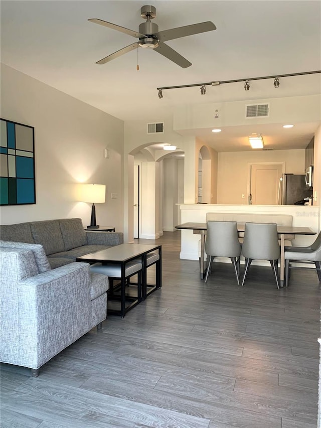 living room featuring dark wood-type flooring, ceiling fan, and track lighting