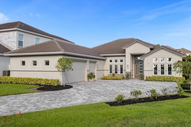 view of front of property with a front lawn, central air condition unit, and a garage