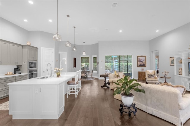 kitchen featuring sink, gray cabinets, oven, a center island with sink, and built in microwave