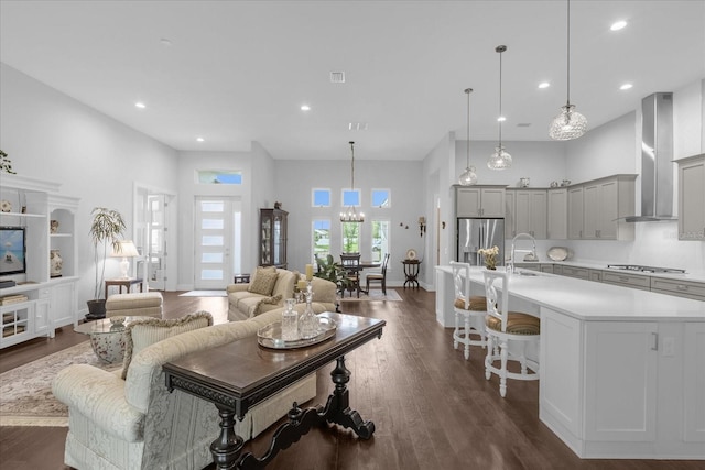 living room featuring dark hardwood / wood-style flooring, sink, a high ceiling, and a notable chandelier