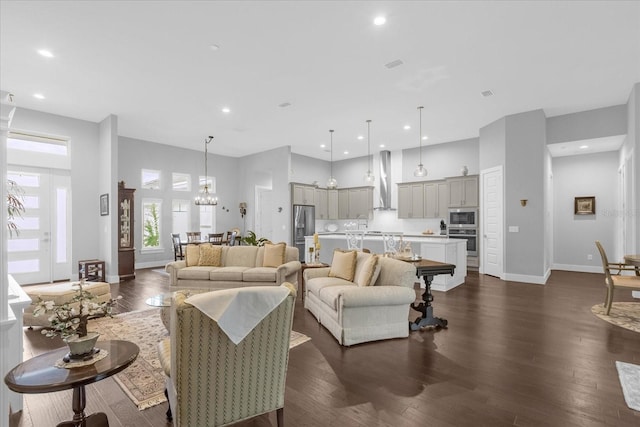 living room featuring dark hardwood / wood-style flooring, a towering ceiling, and a chandelier