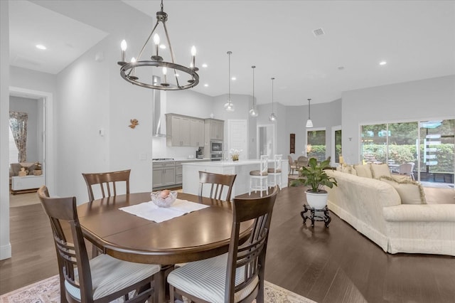 dining room featuring a chandelier, a towering ceiling, and hardwood / wood-style floors