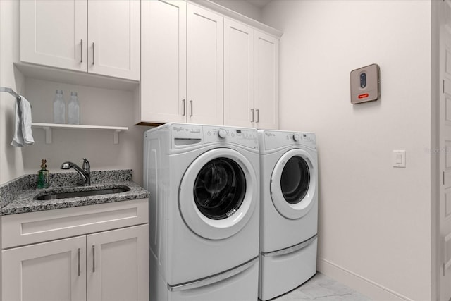 clothes washing area with cabinets, separate washer and dryer, and sink