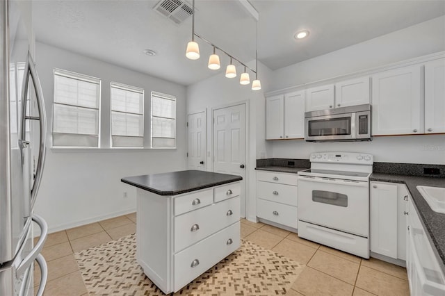 kitchen with pendant lighting, a center island, appliances with stainless steel finishes, light tile patterned flooring, and white cabinetry