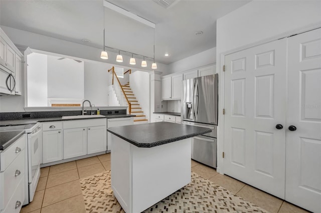 kitchen featuring stove, sink, decorative light fixtures, stainless steel fridge with ice dispenser, and a kitchen island