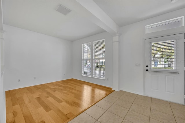 entryway with beam ceiling, decorative columns, and light tile patterned floors