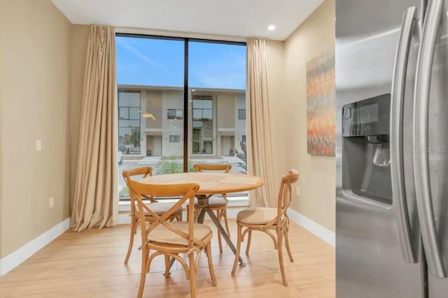 dining space featuring baseboards, light wood-style flooring, and floor to ceiling windows