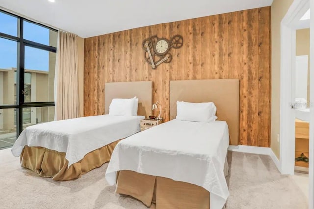 carpeted bedroom featuring a wall of windows, baseboards, and wooden walls