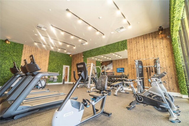 gym featuring wood walls and track lighting