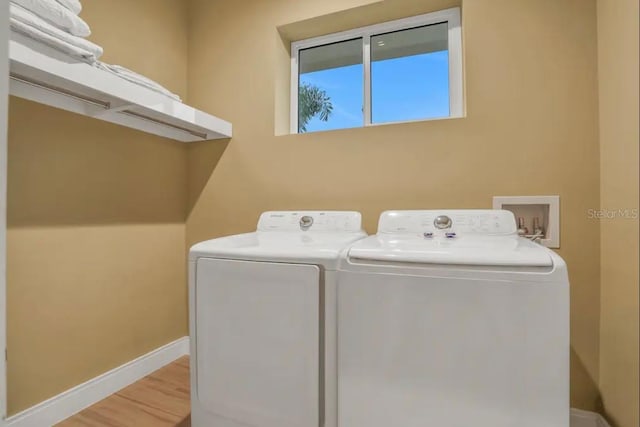 clothes washing area with washer and dryer, laundry area, wood finished floors, and baseboards