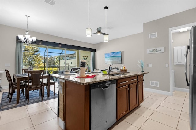 kitchen with a chandelier, pendant lighting, appliances with stainless steel finishes, sink, and light stone counters