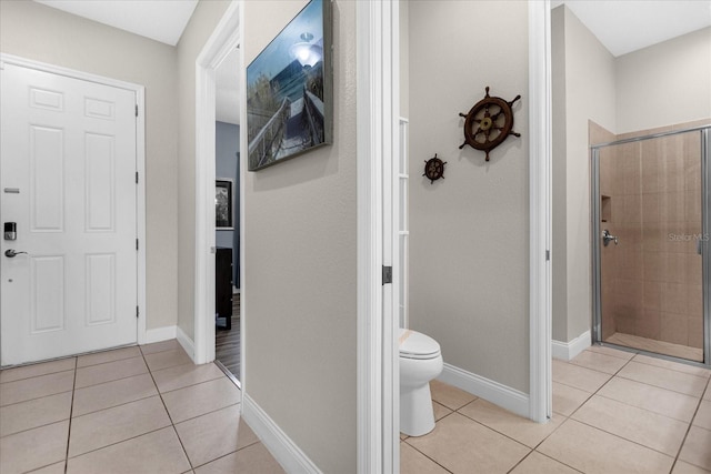 bathroom with toilet, a shower with shower door, and tile flooring