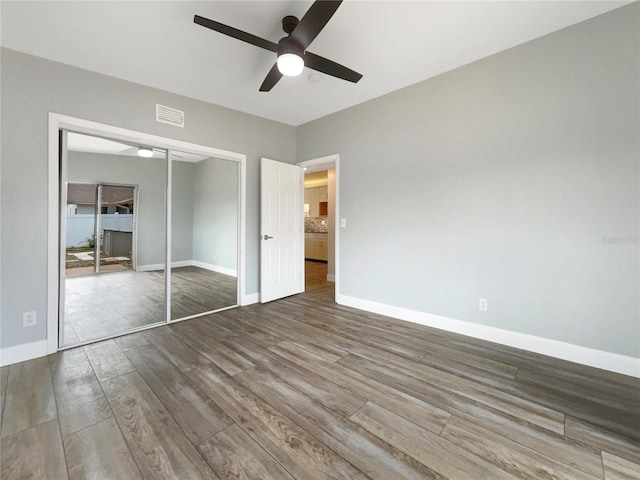 unfurnished bedroom with hardwood / wood-style floors, a closet, and ceiling fan