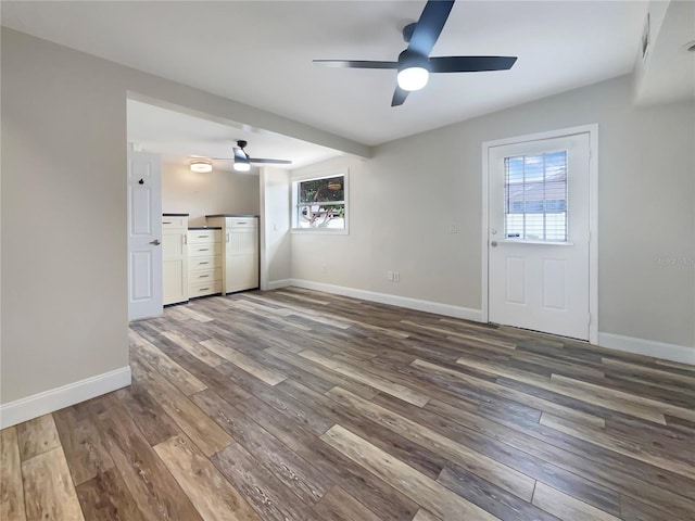 unfurnished living room with ceiling fan and dark wood-type flooring