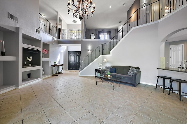 tiled living room with a notable chandelier, built in shelves, and a high ceiling