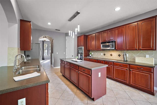 kitchen featuring sink, stainless steel appliances, tasteful backsplash, decorative light fixtures, and a kitchen island