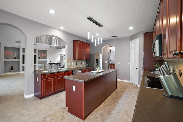 kitchen with a center island, built in shelves, light tile patterned floors, appliances with stainless steel finishes, and decorative light fixtures